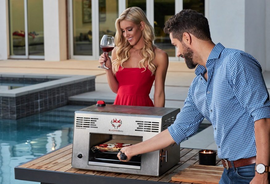Man and wife cooking pizza in the Blazing Bull Portable Infrared Grill